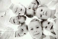 a group of young children standing in a circle looking up at the camera with their heads together