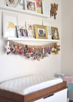 a baby's crib with pictures on the wall above it and other items