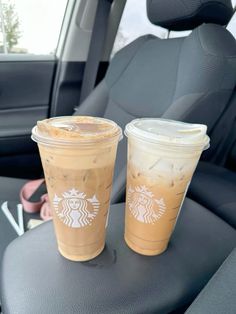 two cups of iced coffee sitting on the back seat of a car