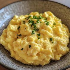 scrambled eggs with parsley on top in a gray bowl, ready to be eaten