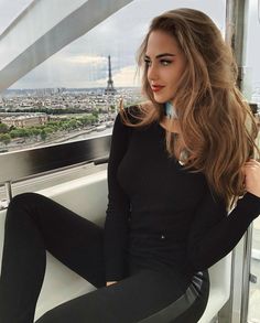 a beautiful woman sitting on top of a window sill next to the eiffel tower