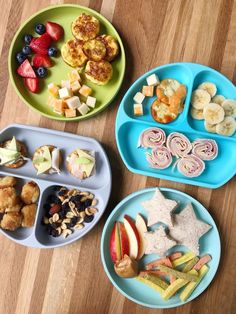 four plates filled with food on top of a wooden table next to fruit and vegetables