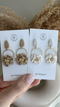 three flower earrings are shown in front of a white card