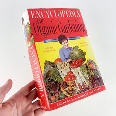 a person holding up a book in their hand with the title encycloppedia of organic gardening