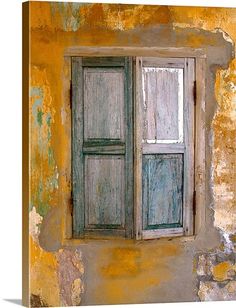 an old window with green shutters is painted on the side of a yellow wall