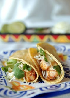 two shrimp burritos on a blue and white plate with cilantro garnish