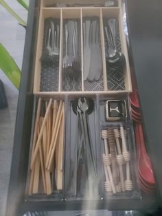 an open drawer with utensils and spoons in it on a table top