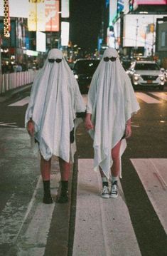 two people in ghost costumes walking down the street