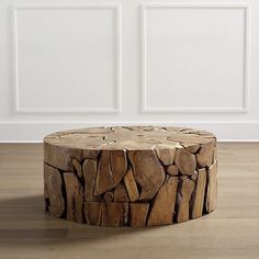 a wooden table made out of logs on a hard wood floor with white walls in the background