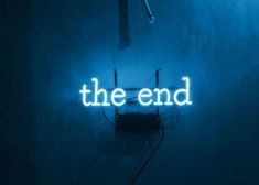 a neon sign that reads the end in front of a dark room with blue walls