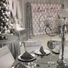 a table set with silver and white decorations