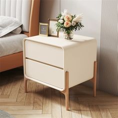 a white nightstand with flowers on it next to a bed and a framed picture frame