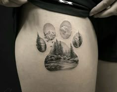 a person with a tattoo on their thigh that has trees and mountains in the background