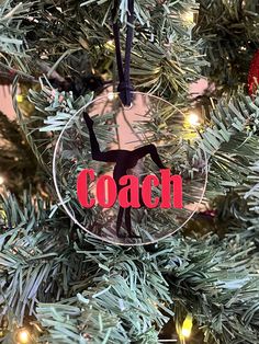 a glass ornament hanging from a christmas tree with the word coach on it