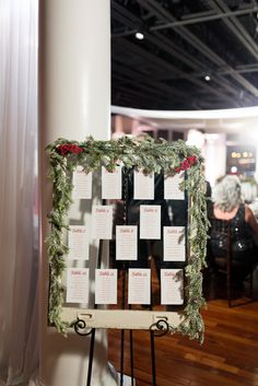 a sign with christmas decorations on it sitting in front of a white pillar and wooden floor