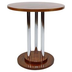 a round wooden table with two metal columns on the top and one white column at the base