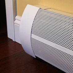 a white speaker sitting on top of a hard wood floor next to a yellow wall