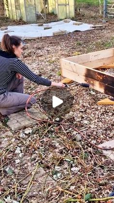 a woman kneeling down next to a wooden box filled with dirt and wood planks