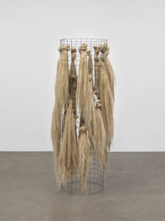 three long hair hanging from a wire rack on the floor in front of a white wall