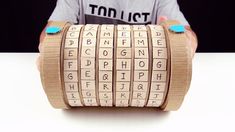 a person is holding up a roll of wood with letters on it