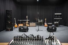 a recording studio with sound equipment and microphones on the floor in front of black curtained walls