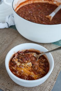 a white bowl filled with chili and beans next to a casserole dish on a table