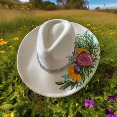 Introducing our stunning white felt cowboy hat, adorned with a touch of sparkle and a splash of charm. Handcrafted with care and attention to detail, this one-of-a-kind hat is the perfect statement piece for any occasion. The rhinestone band adds a touch of glamour, while the hand-painted floral motif brings a touch of nature's beauty to your look. Each hat is adjustable, ensuring a comfortable and secure fit for all-day wear. The delicate floral design is inspired by the beauty of nature, making it a truly special accessory to elevate your outfit. Whether you're heading to a festival, a country concert, bachelorette party or just want to add some flair to your everyday style, this cowboy hat is sure to turn heads and spark conversations. Treat yourself or give it as a unique and thoughtfu White Fedora For Kentucky Derby, White Adjustable Felt Hat With Curved Brim, White Adjustable Curved Brim Felt Hat, White Brimmed Felt Hat For Kentucky Derby, White Flat Brim Felt Hat For Summer, White Western Felt Hat For Kentucky Derby, White Felt Hat With Short Brim For Summer, Western White Felt Hat With Curved Brim, White Western Felt Hat With Curved Brim