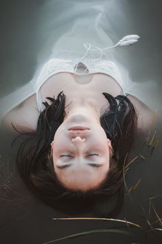 a woman is floating in the water with her eyes closed