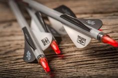 three darts sitting on top of a wooden table next to each other with red tips