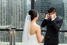 a bride and groom standing next to each other in front of a cityscape