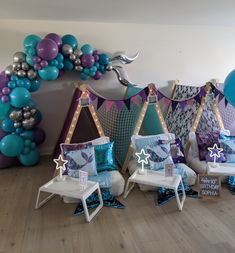 a room filled with lots of balloons and furniture next to a wall that has mermaid decorations on it