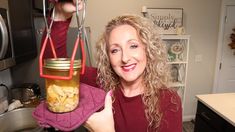 a woman holding a jar with food in it and hanging from the ceiling above her head