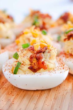 deviled eggs stuffed with bacon and cheese on a wooden cutting board, ready to be eaten