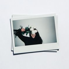 a polaroid photo of a woman with flowers on her head and hair in the air