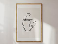 a black and white drawing of a coffee cup in a wooden frame on the wall