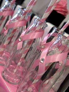 there are many empty wine bottles with pink ribbons on them