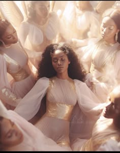 a group of women in white dresses surrounded by angel wings and gold sequins