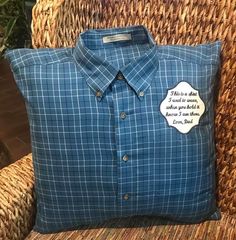 a blue shirt with a white patch on it sitting on a wicker chair next to a pillow