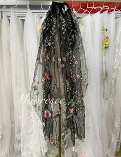 a white dress with flowers and vines on it is displayed in front of sheer curtains