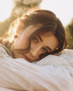 a woman laying on top of a white blanket