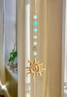 the sun and moon necklace is hanging in front of a curtain with beads on it