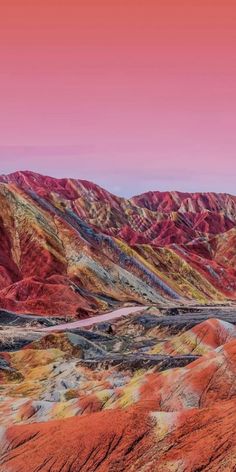 the mountains are covered in red and orange colors, with a road running through them