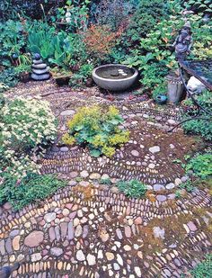 an outdoor garden with stones and plants in the ground, surrounded by trees and shrubs