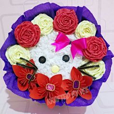 a hello kitty made out of rice with red and white flowers on it's face