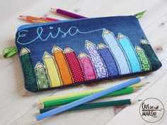 an embroidered pencil case with colorful crayons on it