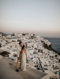 a bride and groom standing on the roof of a building in oia, greece