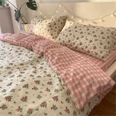 an unmade bed with pink and white flowers on the comforter, pillows and sheets