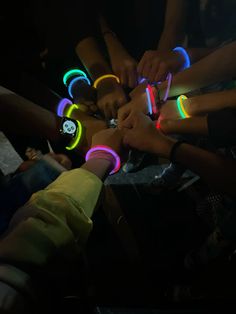 a group of people standing around each other with neon lights on their wristbands