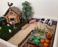 there are many farm animals in the toy house with fake grass and rocks on the ground