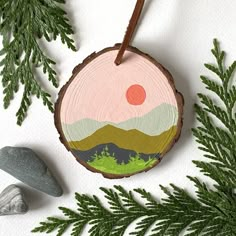 a wooden ornament hanging from a tree branch next to some rocks and plants